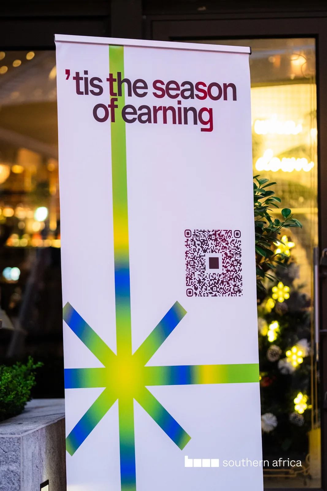 Base southern africa roll-up banner reading “’tis the season of earning” with a QR code