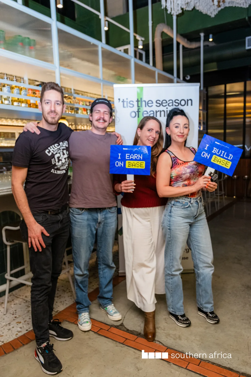 Four people holding Base campaign cards at an indoor activation